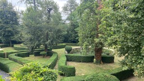 A meticulously landscaped garden with geometric hedges and a variety of trees. - hotel restaurant LEs Boissières (Bioule)