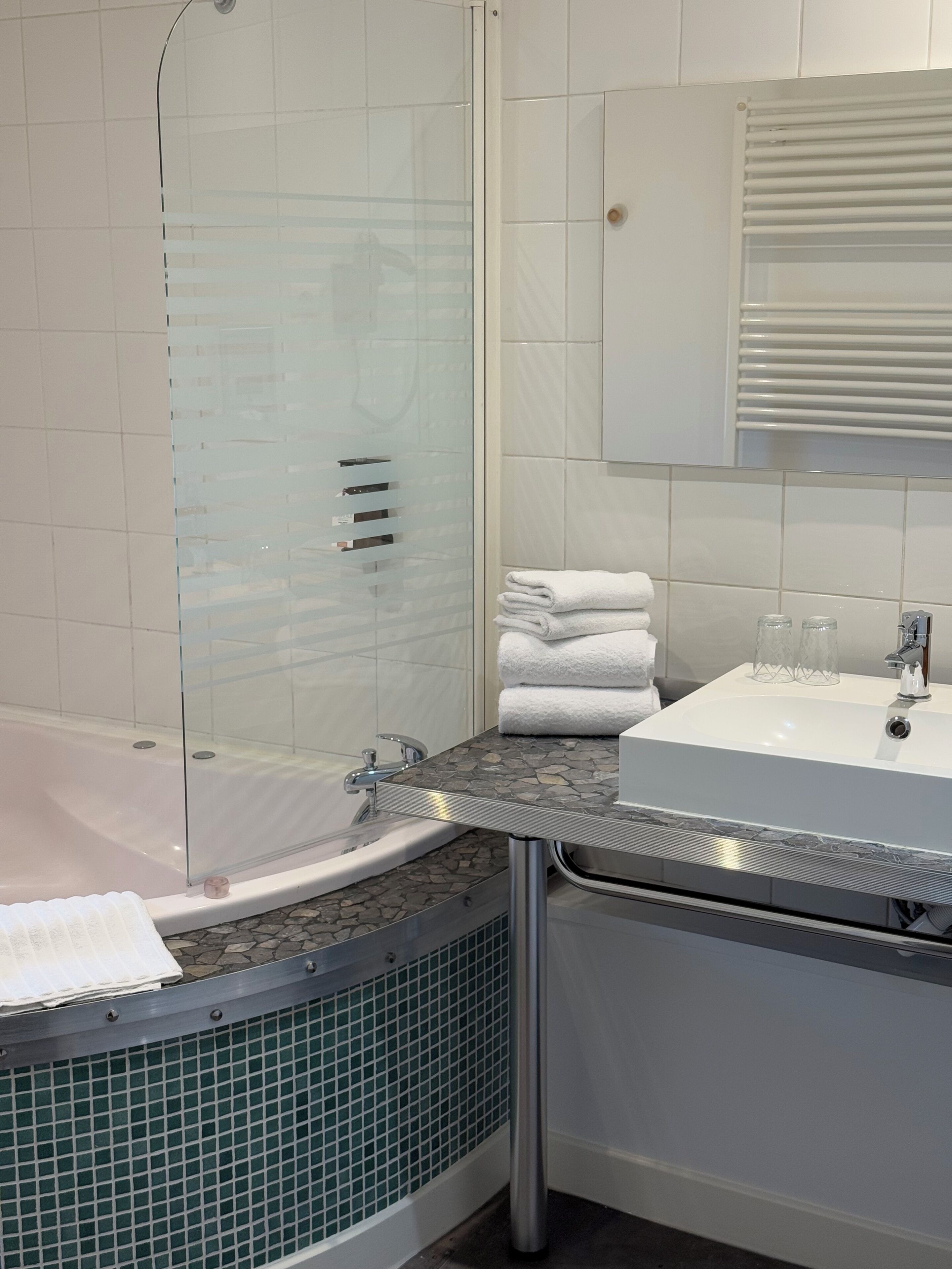 Un baño con ducha envuelta en vidrio, un lavamanos blanco y un espejo sobre él.