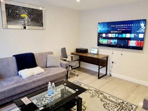 Una sala de estar moderna con sofá, mesa de centro, televisor y escritorio.