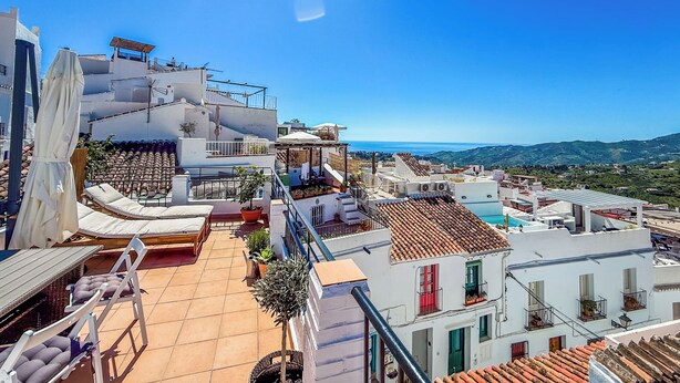 Une terrasse sur le toit avec des sièges extérieurs, une piscine et une vue sur la mer et les collines.