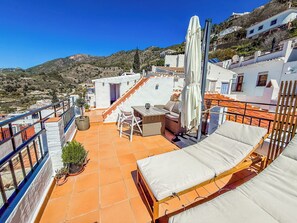 A rooftop terrace with a dining area, a sofa, and a sun umbrella. - Two bed House With Roof Terrace in the Beautiful Village of Frigiliana (Frigiliana)