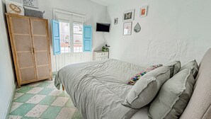 Une chambre à coucher avec un lit, une armoire, une télévision et une fenêtre avec des volets bleus.