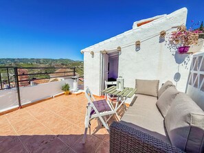 A rooftop terrace with a white wall, a wicker sofa, a small table, and a chair. - Two bed House With Roof Terrace in the Beautiful Village of Frigiliana (Frigiliana)