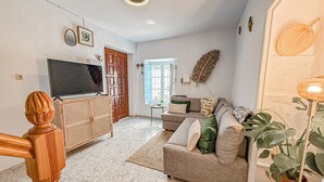 Un salon avec un canapé, un téléviseur, un meuble en bois et une plante.