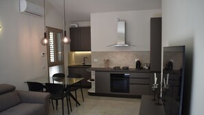 Eine moderne Küche mit Essbereich, ausgestattet mit einer Couch, Stühlen, einem Tisch und einem Einbauofen.