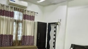 A bedroom with a bed, a wardrobe, a mirror, and an air conditioning unit.