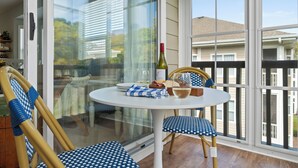 Un coin repas avec une table ronde, deux chaises et une bouteille de vin.