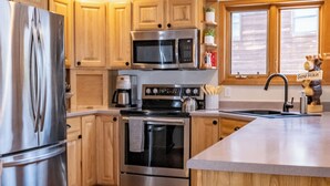 A modern kitchen with stainless steel appliances, wooden cabinets, and a large island. - Spacious Mountain Home with Private Hot Tub (Granby)
