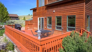 A wooden house with a deck, a barbecue grill, and a table with chairs. - Spacious Mountain Home with Private Hot Tub (Granby)