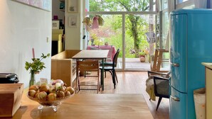 A kitchen with a wooden table, chairs, a blue refrigerator, and a view of greenery outside. - Bright, quiet apartment with terrace and large natural garden. Lake and train station nearby (Utting am Ammersee)