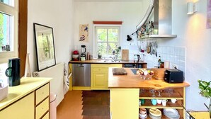 A compact kitchen with wooden flooring, a built-in sink, and a window providing natural light. - Bright, quiet apartment with terrace and large natural garden. Lake and train station nearby (Utting am Ammersee)