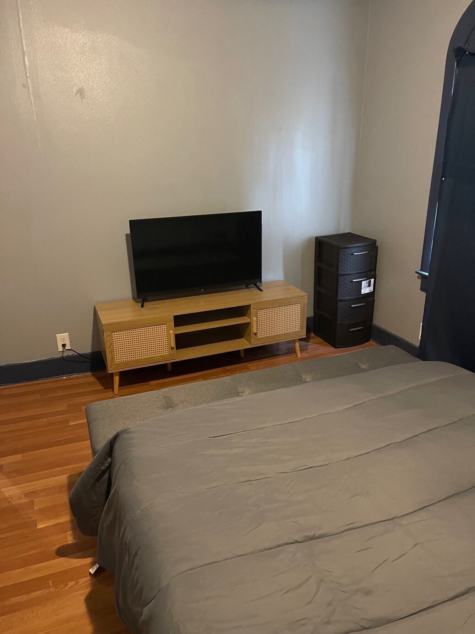 Un dormitorio con una cama, un televisor sobre un mueble de madera y un archivador.
