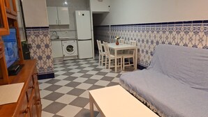 Une cuisine compacte équipée d’un lave-linge, d’une table à manger avec des chaises et d’un canapé.