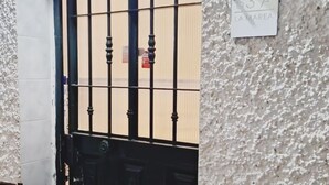 Une entrée sécurisée, dotée d’un portail en métal, d’une caméra de surveillance et d’un panneau indiquant la présence d’un service de sécurité disponible 24 heures sur 24.