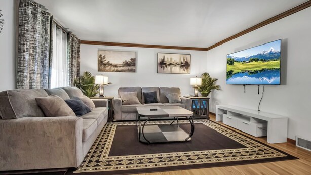 Un salon moderne avec deux canapés, une table basse et un téléviseur fixé au mur.
