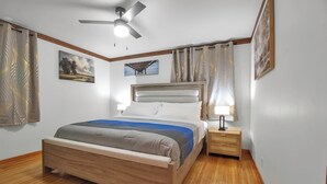 Une chambre à coucher avec un lit en bois, un ventilateur de plafond et une table de chevet avec une lampe.
