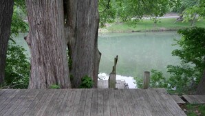 A wooden deck with a view of a lake, surrounded by trees.