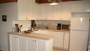 A kitchen with white cabinets, a microwave, a refrigerator, a sink, and a coffee maker.