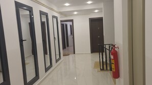 A hallway with multiple doors, a fire extinguisher mounted on the wall, and a clean, tiled floor. - A rare pearl (Oran)