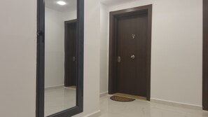 A hallway with a dark wooden door marked with the number 24, a tiled floor, and a small rug at the door's entrance.