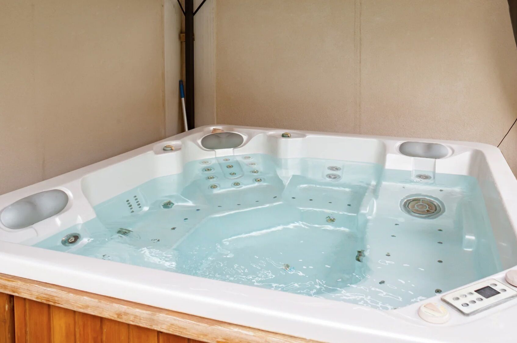 Ett rektangulärt bubbelbad med flera munstycken, en kontrollpanel och ett avlopp.