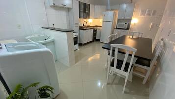 Una cocina moderna con armarios blancos, una mesa de comedor con sillas y un ventilador de techo.