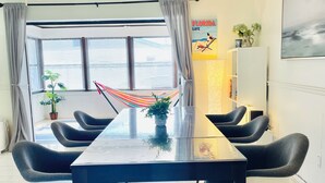 A dining area with a long table, black chairs, a ceiling fan, and a hammock.