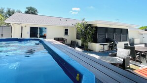 A backyard with a swimming pool, outdoor furniture, and a house.