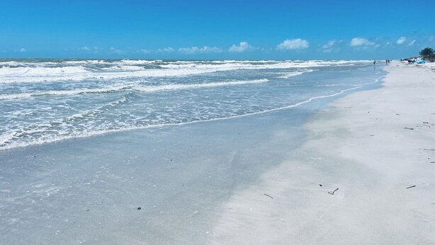 A beach with waves and a clear sky.