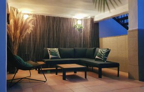 A sectional sofa with a wooden coffee table, a single chair, and a hanging plant.