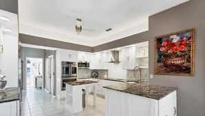 A spacious kitchen with white cabinetry, granite countertops, and a large island. - Luxury home NW Bradenton Fl (Bradenton)