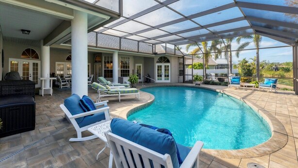 A covered outdoor swimming pool with lounge chairs and a patio area. - Luxury home NW Bradenton Fl (Bradenton)
