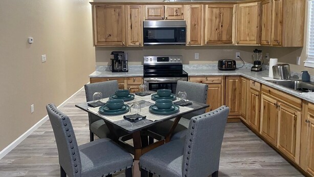 A modern kitchen with wooden cabinets, a stainless steel microwave, a stove, and a coffee maker. - Cozy New Apartment in Fairbanks (Fairbanks)