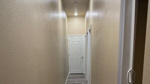 A narrow hallway with beige walls and a wooden floor. - Cozy New Apartment in Fairbanks (Fairbanks)