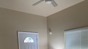 A bedroom with a bed, a ceiling fan, a door with a window, and a nightstand with a lamp. - Cozy New Apartment in Fairbanks (Fairbanks)