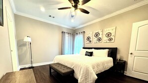 A bedroom with a bed, a bench, a ceiling fan, and artwork on the wall. - Spacious 3BR Auburn Getaway – Family-Ready and Near All Auburn Has to Offer (Auburn)
