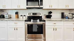 A modern kitchen with white cabinets, stainless steel appliances, and a granite countertop. - Spacious 3BR Auburn Getaway – Family-Ready and Near All Auburn Has to Offer (Auburn)