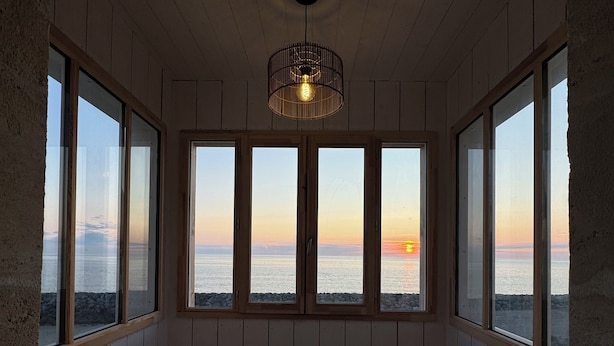 A room with wooden benches and large windows overlooking a sunset.