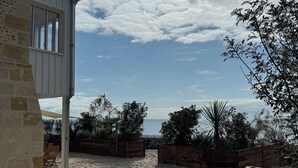 A beach house with a patio, wooden fences, and a view of the ocean.