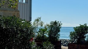 A coastal building with a stone facade, a window, and a view of the sea.