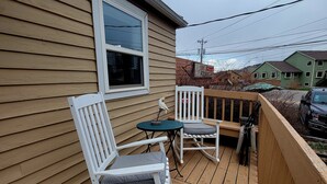A wooden deck with two rocking chairs and a small table. - Comfortable and Cozy 1-bedroom house in delightful Rapid City with AC & Wifi (Rapid City)