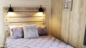 A bedroom with a wooden headboard, two bedside lamps, and a motivational quote on the wall. - Comfortable and Cozy 1-bedroom house in delightful Rapid City with AC & Wifi (Rapid City)