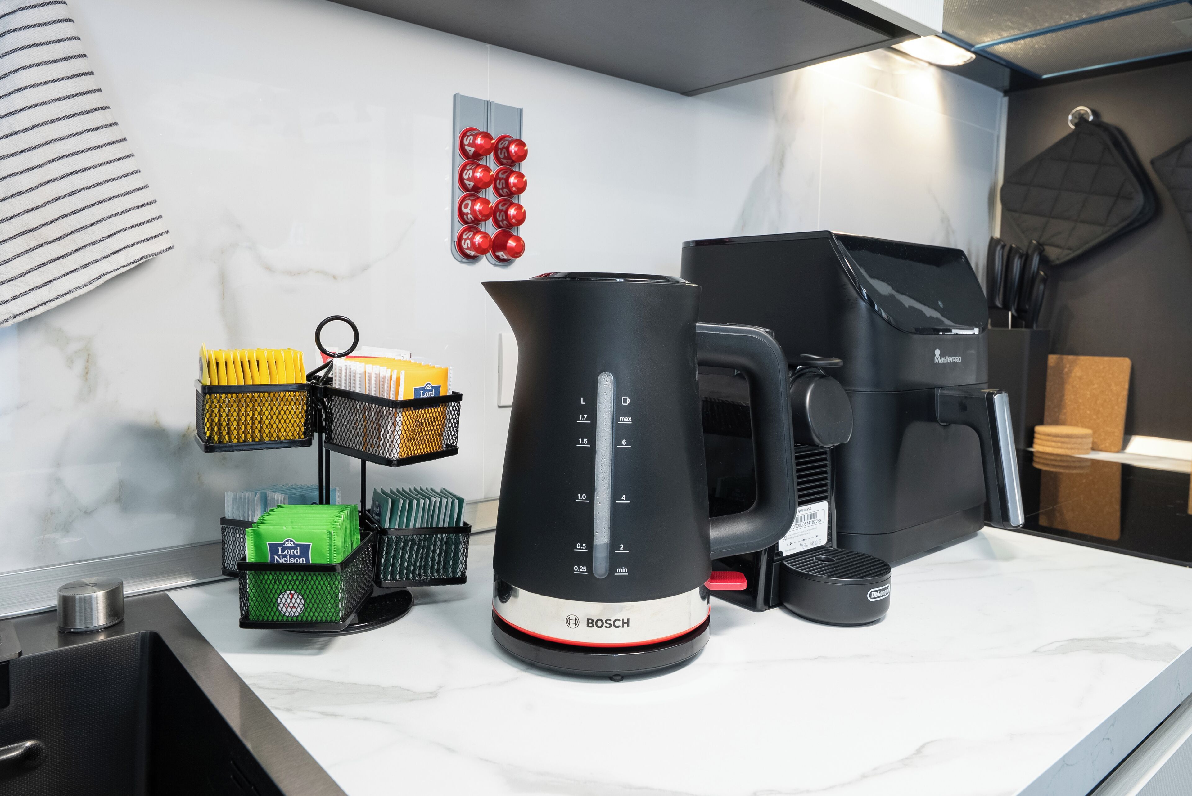 Een aanrecht met een Bosch koffiezetapparaat, een waterkoker en een koffiemolen.