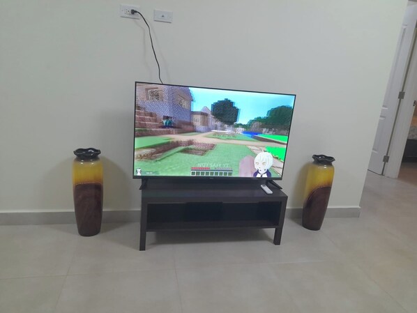 Un televisor sobre un pedestal en una habitación con piso de baldosas.