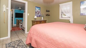 A bedroom with a large bed, a dresser, a nightstand, a lamp, and a poster on the wall. - Charming 1-bedroom private apartment in a cottage with AC & WiFi (Colorado Springs)