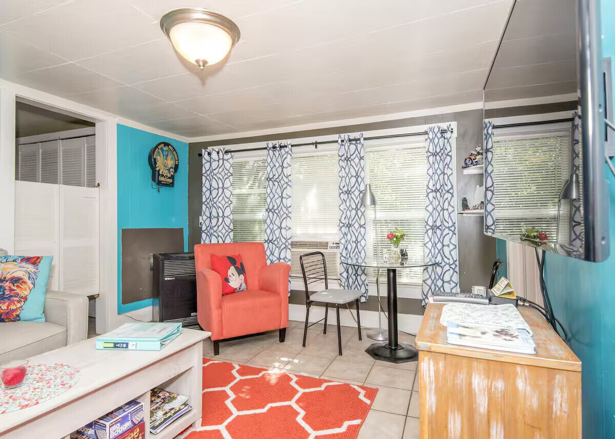 A compact living space with a sofa, a red chair, a small table, and a TV.