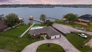 Une propriété résidentielle dotée d’un grand garage, d’une piscine et d’un quai s’avançant dans un lac.