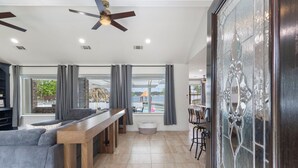 Un vaste espace de vie comprenant un canapé, une table basse en bois et une vue sur une piscine et un espace de détente extérieur.