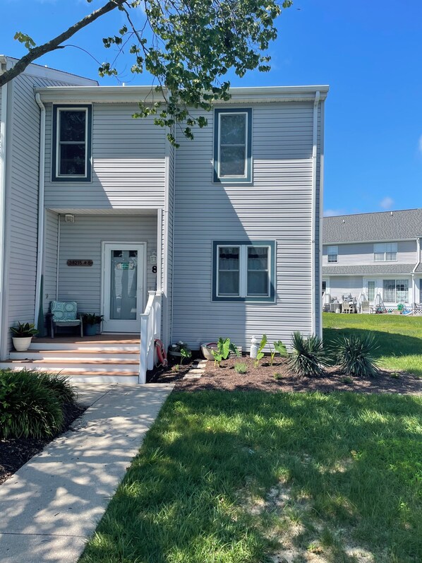 A two-story house with a front porch, a mailbox, and a small garden.