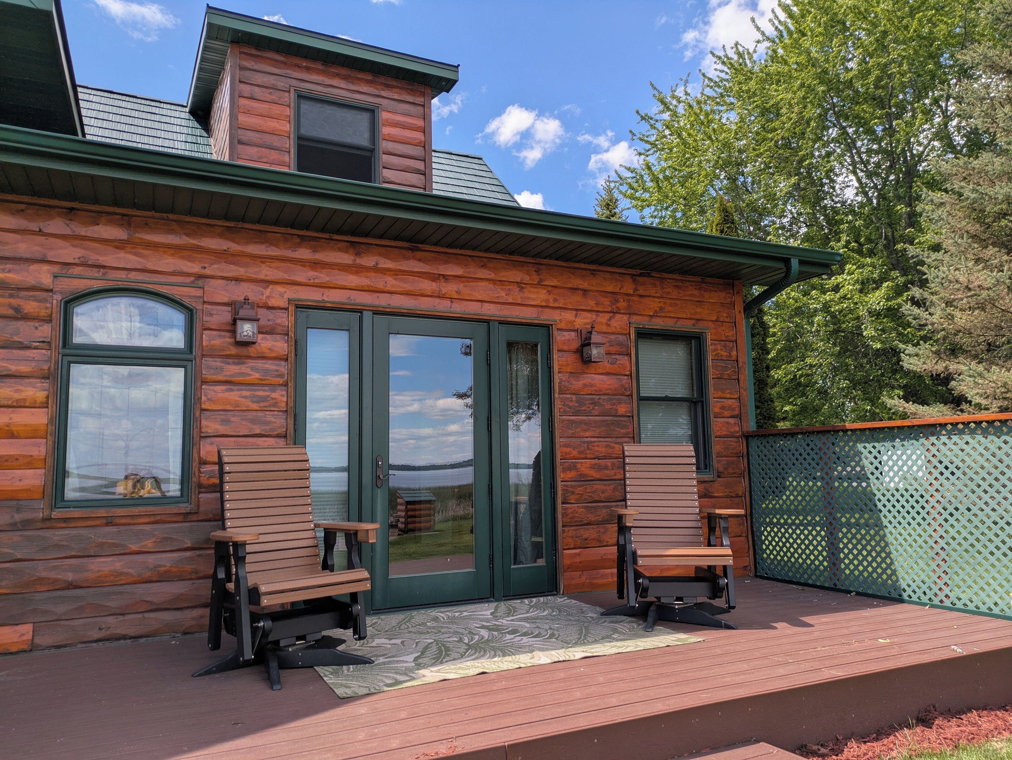 Une cabane en bois dotée d’une terrasse, de deux chaises et offrant une vue sur un lac.